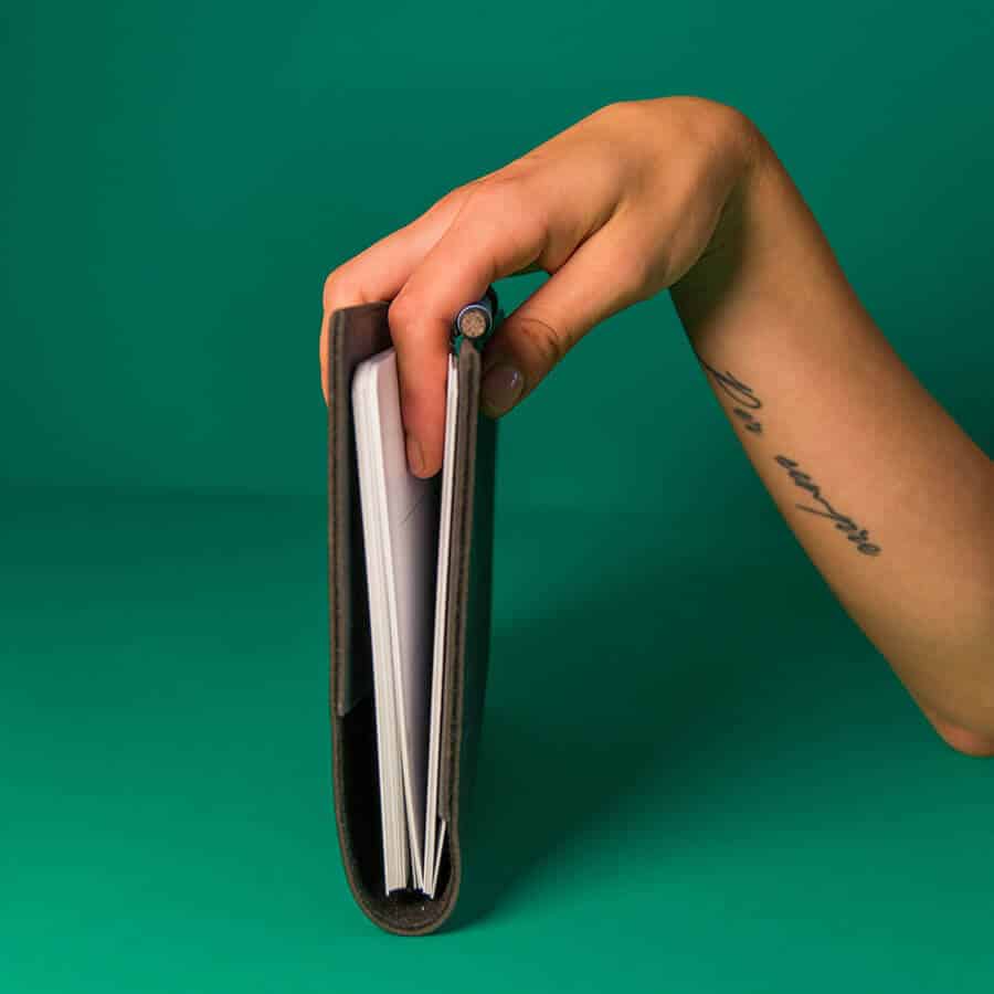 eine Hand hält ein gefaltetes, löschbares Tagebuch mit veganem Ledereinband