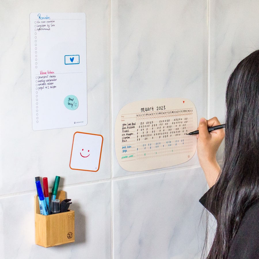 Eine Frau schreibt auf den fertigen Sticky Whiteboard Gewohnheits-Tracker.