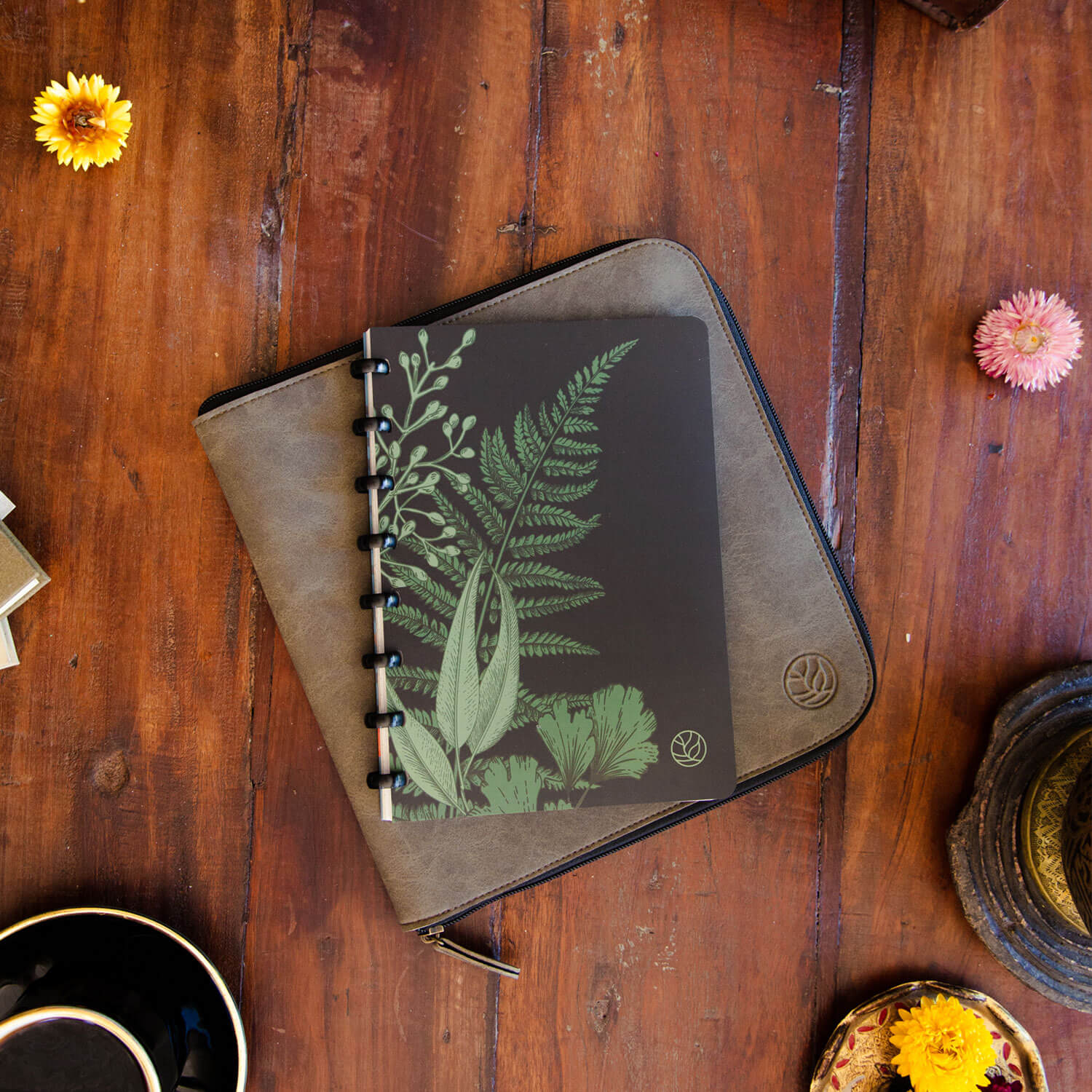 greenbook all in one mit einem waldgrünen Einband liegt auf einer Arbeitsmappe aus Ton mit einem Holztisch als Unterlage